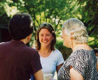 Staff and students talking, smiling, in sunlight in St Clare's garden