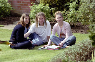 Two young female and one young male student studying in St Clare's garden, in sunshine