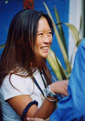 Closeup of a St Clare's student, female, young, smiling, in white T-shirt, outside in sunlit garden