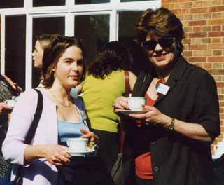 Young woman and older woman, with cups of tea in sunlit St Clare's garden