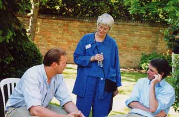 Two young men with woman staff member, in sunlit St Clare's garden