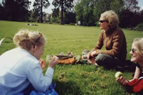 Three St Clare's students sitting on the grass in an Oxford garden