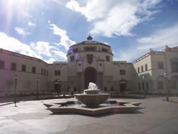 Exterior view of the Joan B. Kroc Institute for Peace and Justice, with small fountain, blue sky and clouds above