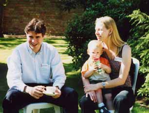 Young man and young woman with small child seated, in sunlit St Clare's garden