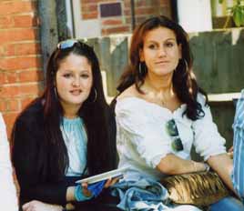 Two young women looking into camera, in sunlit St Clare's garden