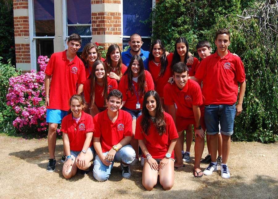 A group of student in red t-shirts in sunshine in a garden