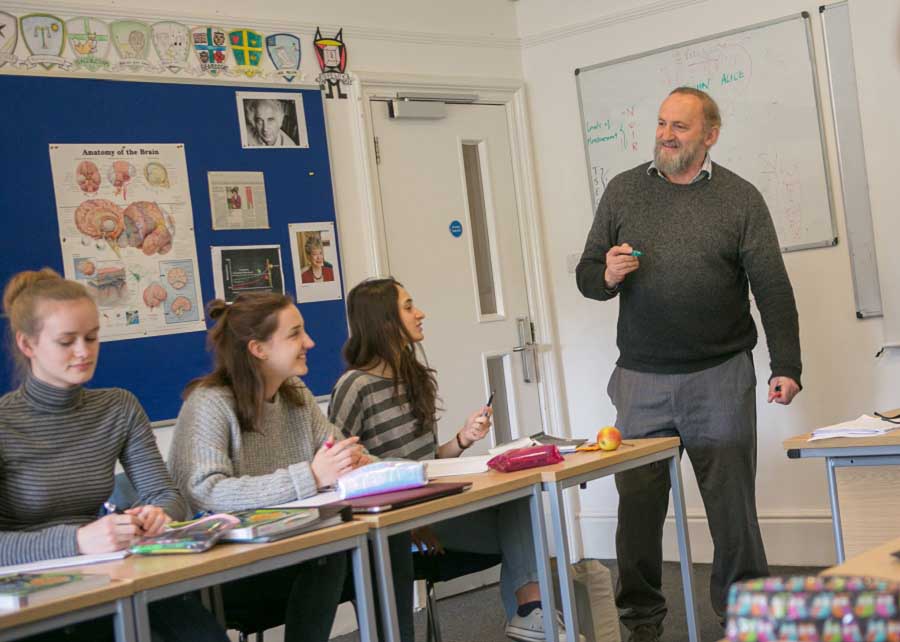 IB psychology teacher in classroom teacher in classroom with three students