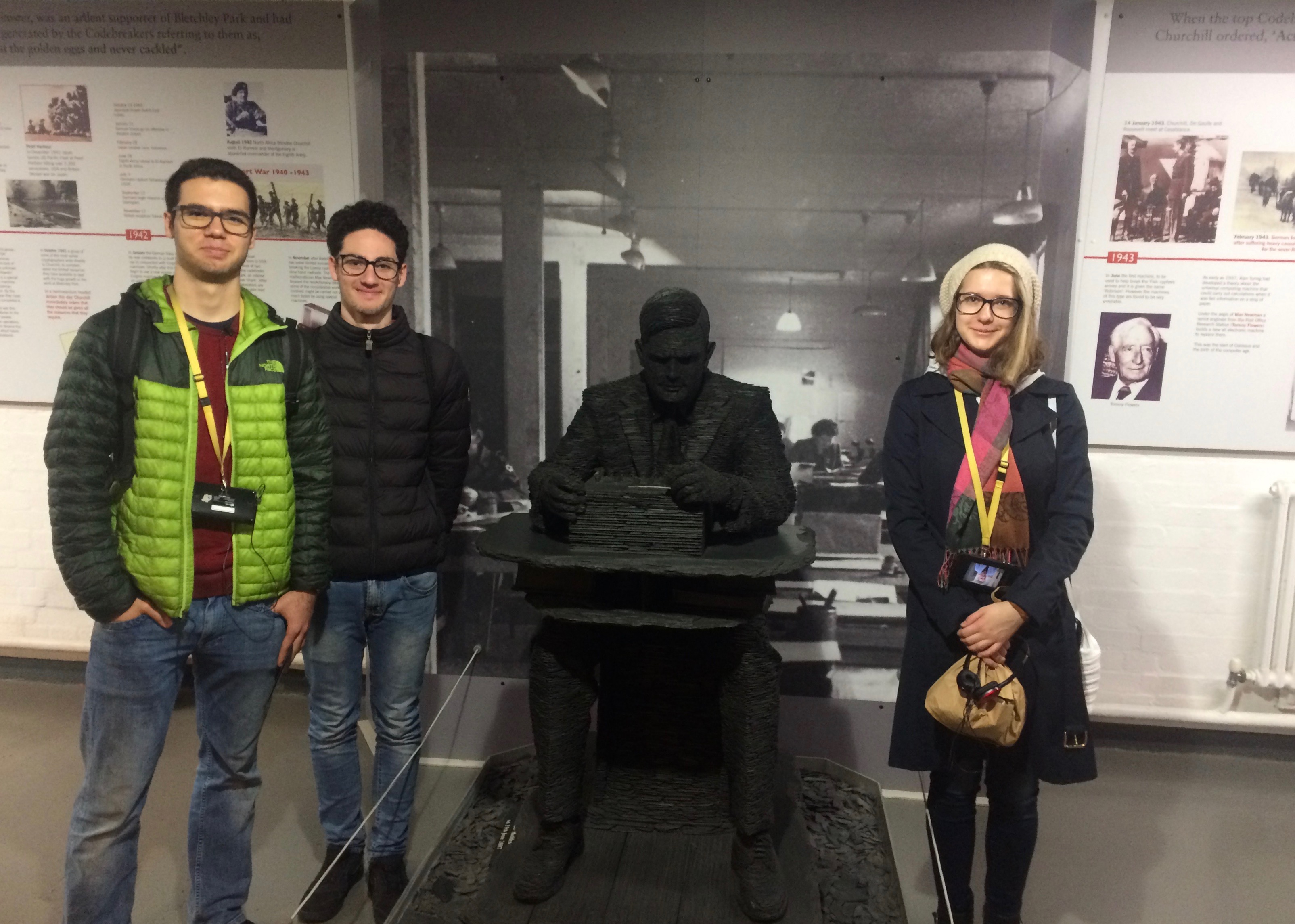 three students posing with statue